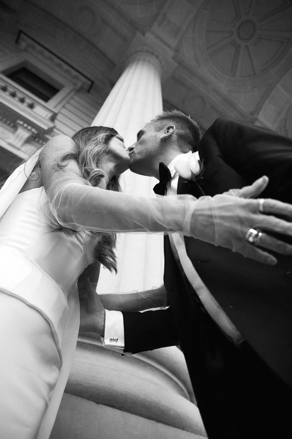 Bride and groom kissing outside a grand Melbourne building — black-and-white wedding photography