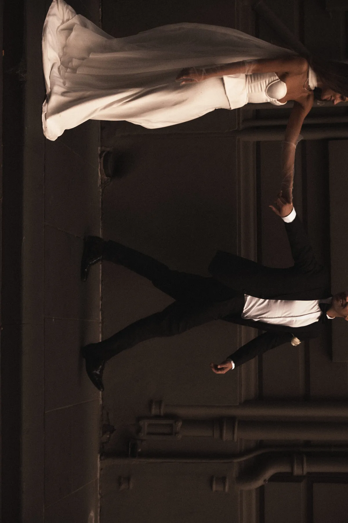 Bride and groom walking together through a dark doorway